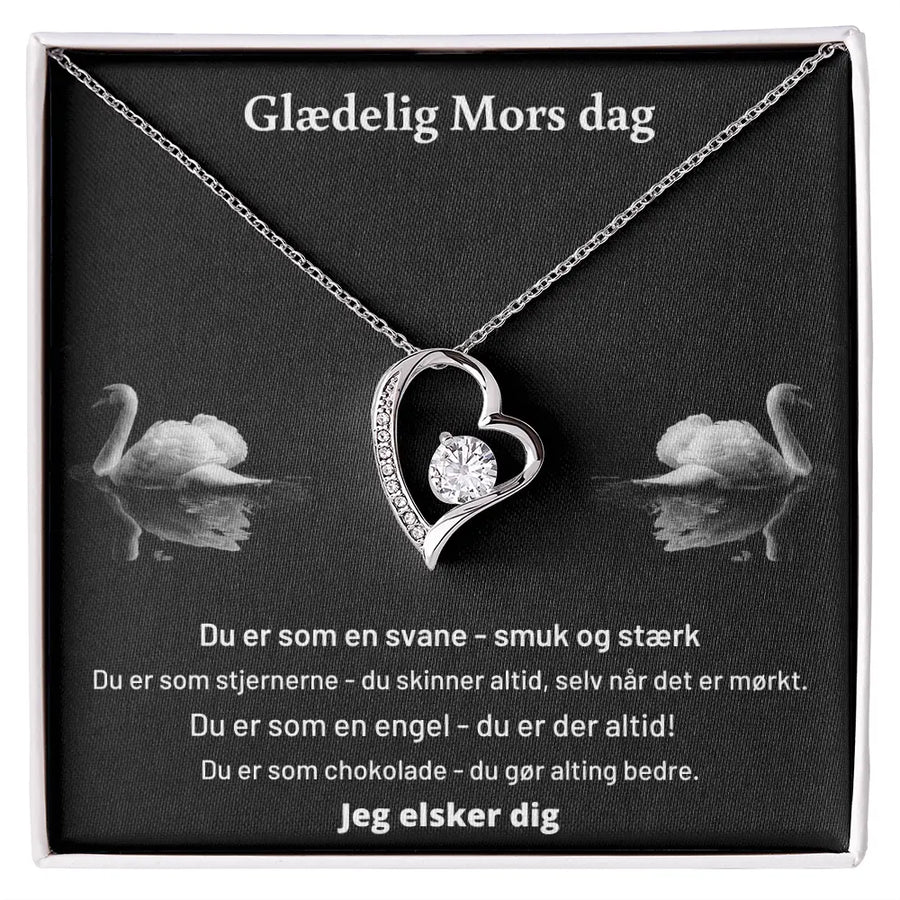 Elegant Forever Love-halskæde i rustfrit stål med 14 karat hvidguld belægning. Det hjerteformede vedhæng prydes af en rund 6 mm Cubic Zirkonia-sten og små klare krystaller, leveret i gaveæske med rørende kort til Mors Dag.