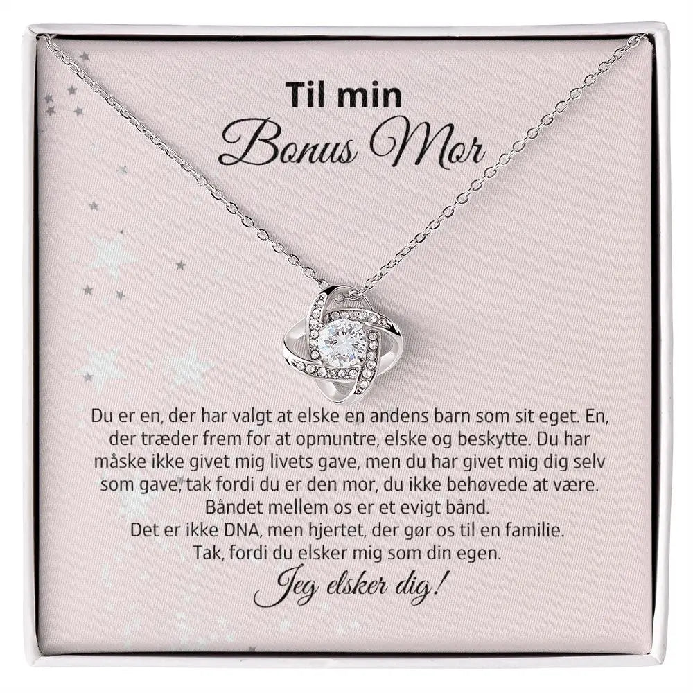 Love Knot-halskæde i rustfrit stål med 14k hvidguldsbelægning og Cubic Zirkonia-sten. Præsenteres i gaveæske med kærlig tekst til bonusmor. En symbolsk og smuk gave til den mor, du har fået med hjertet.